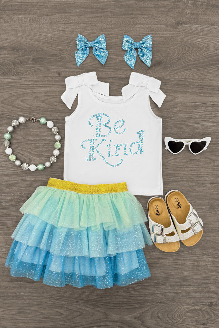 "Be Kind" Glitter Tutu Skirt Set - 6-12 Months - White toddler top with blue "Be Kind" text, layered blue and yellow glitter tutu skirt, matching blue bows, white sandals,.