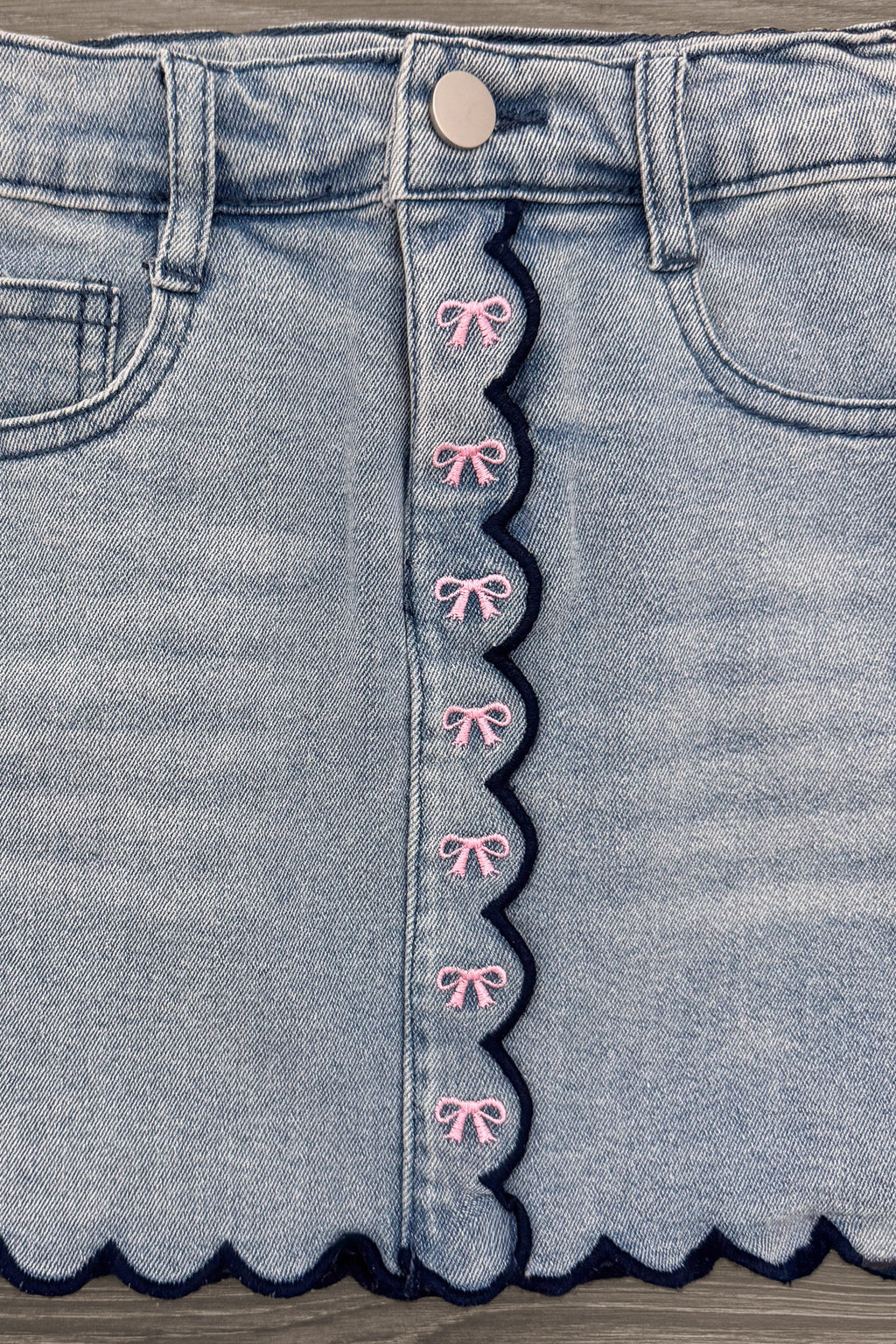 "Pre-K - Fifth Grade" Apple Denim Skirt Set - PRE-K / 2T - Light blue denim skirt with scalloped edges and pink embroidered bows along front button placket.