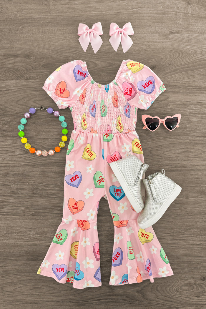 Pink Candy Hearts Bell Bottom Jumpsuit - 3XS-6-12 Months - Pink bell bottom jumpsuit with candy heart print, paired with white boots, heart-shaped pink sunglasses, bead necklace, and.