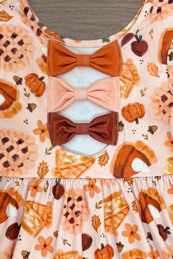 Autumn Pie Ruffle Dress - 6-12 Months - Orange dress with autumn pie and pumpkin print, featuring three stacked fabric bows in rusty orange, peach, and brown on the