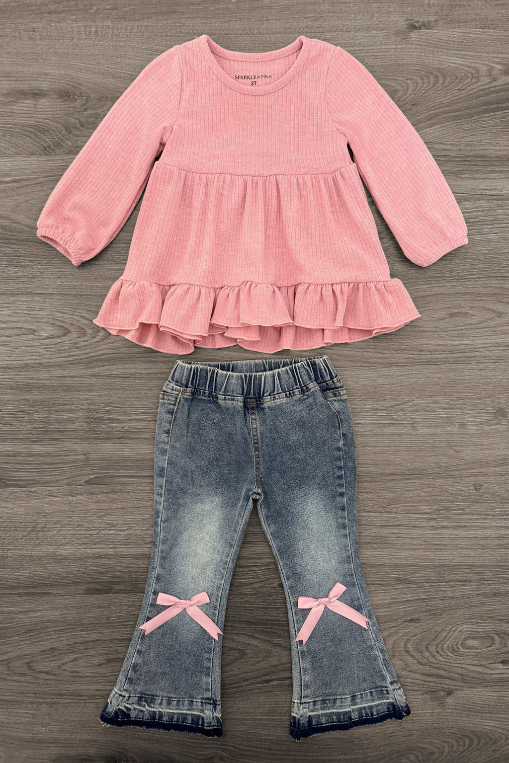 Pink Bow Denim Flare Pant Set - 6-12 Months - Pink long-sleeve top with ruffled hem and light blue denim flared pants featuring pink bow accents at the knees.