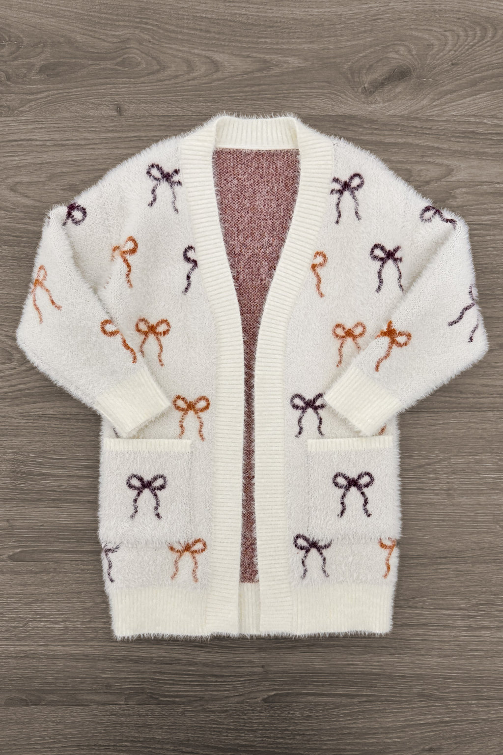 Mom & Me - Cozy Cream Bow Cardigan - CHILD-6-12 Months - Cream knit cardigan with multicolored bow patterns in brown, burgundy, and rust, featuring front pockets and an open front.
