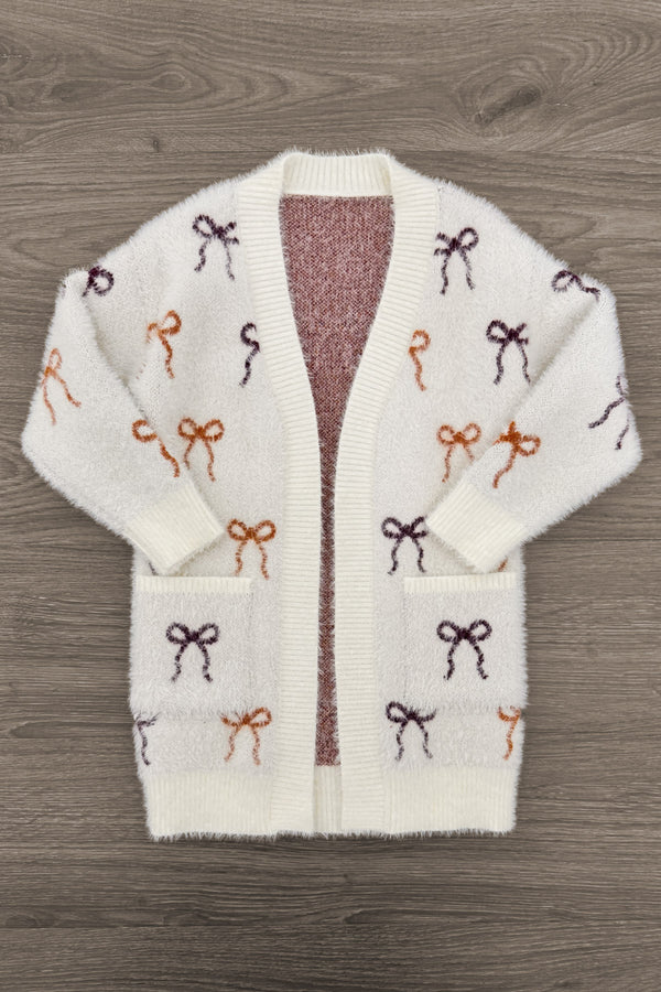 Mom & Me - Cozy Cream Bow Cardigan - CHILD-6-12 Months - Cream knit cardigan with multicolored bow patterns in brown, burgundy, and rust, featuring front pockets and an open front.