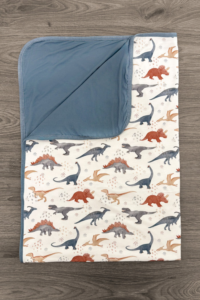 Bamboo Tiny Dino Double Sided Blanket - Default Title - Double-sided baby blanket with blue solid fabric on one side and dinosaur print in blue, orange, and gray on cream.