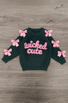 "Wicked Cute" Denim Flare Set - 6-12 Months - Black long-sleeve sweatshirt with pink "wicked cute" text and pink bows on sleeves, laid flat on wood floor.