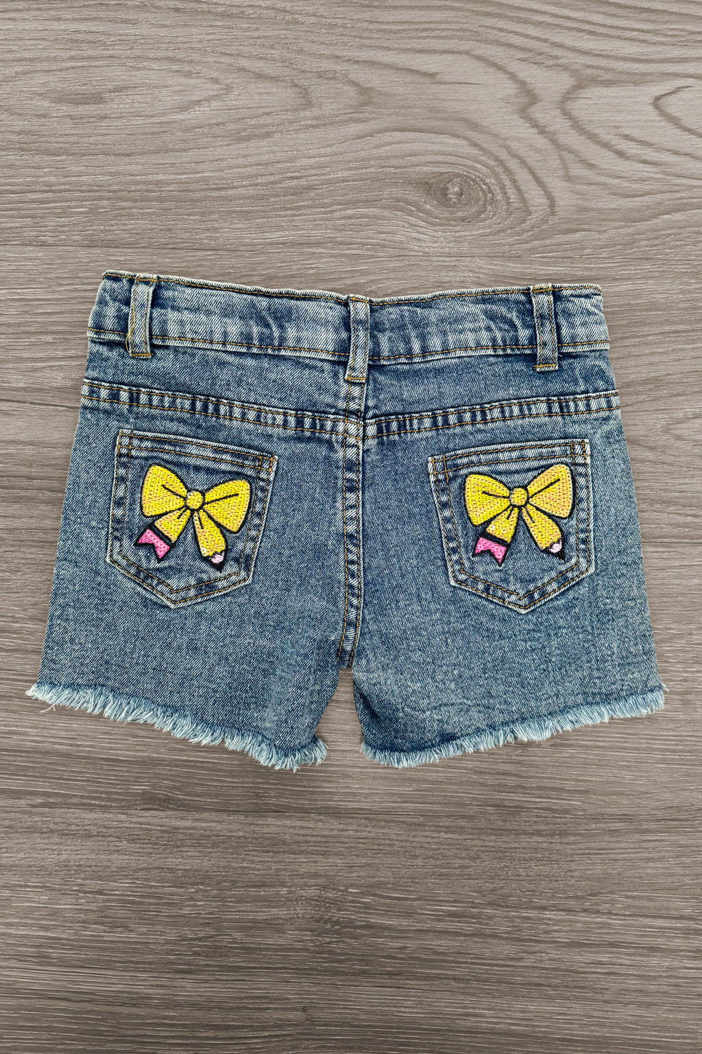 "Pre-K - Sixth Grade" Pink Pearl Denim Short Set - PRE-K / 2T - Child's denim shorts with frayed hems, featuring two back pockets each adorned with a yellow bow graphic print.