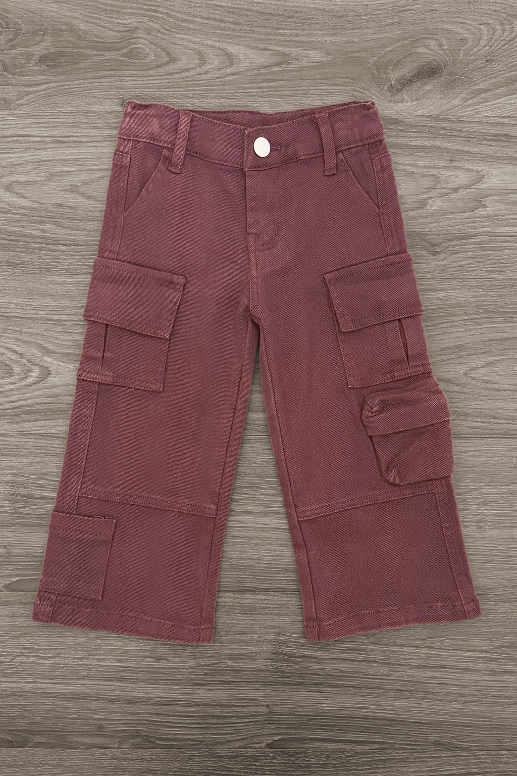 Knit Flower Burgundy Denim Pant Set - 6-12 Months - Burgundy denim cargo pants with multiple flap pockets and wide legs on wooden floor background.