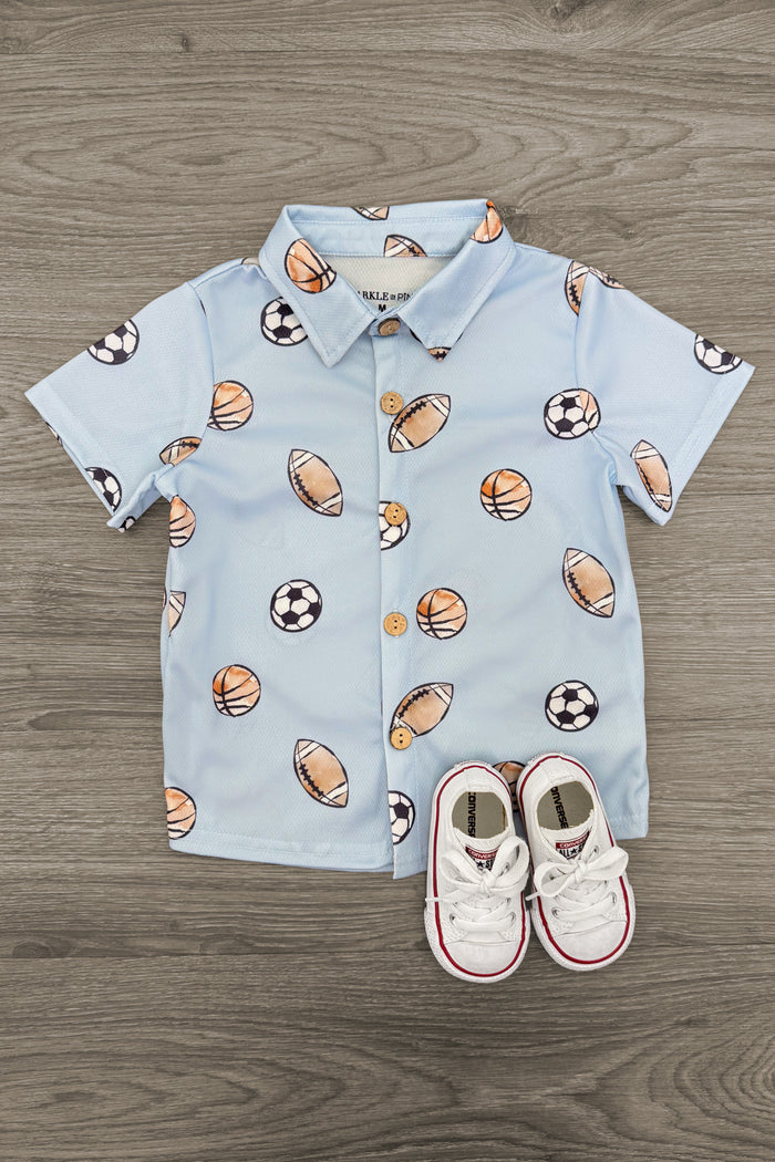 Light Blue Sports Ball Button Down Top - 3XS-6-12 Months - Light blue button-down shirt with sports ball prints and white toddler sneakers.