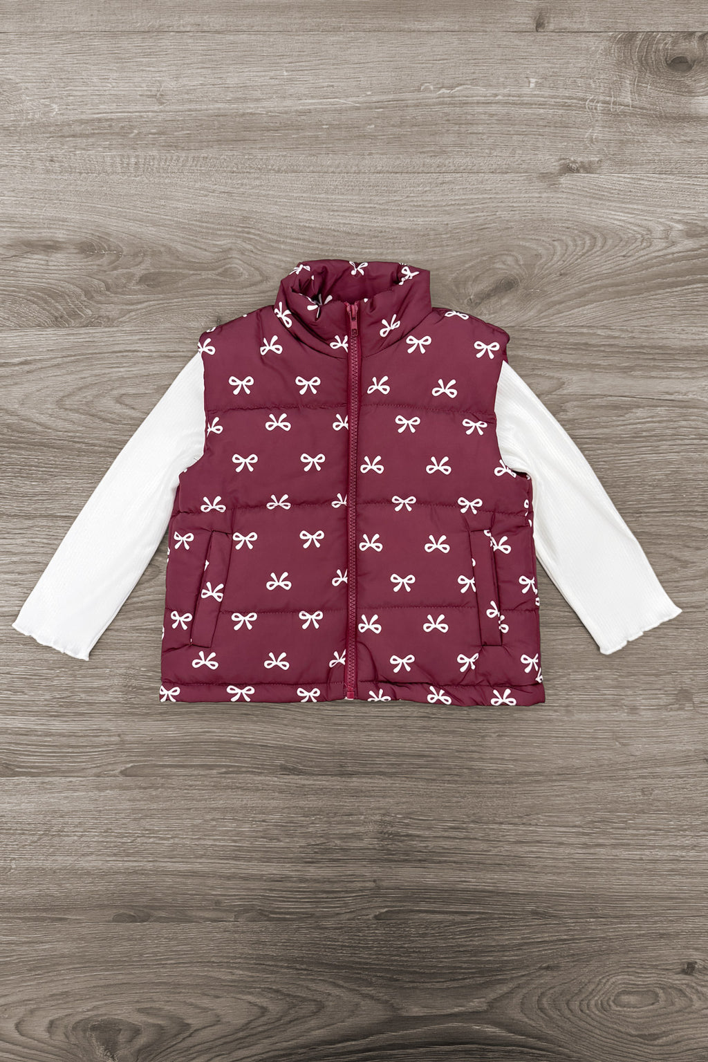 Mom & Me - Bow Vest Set - CHILD-6-12 Months - Burgundy quilted vest with white bow print layered over a long-sleeve white shirt on wooden floor background.