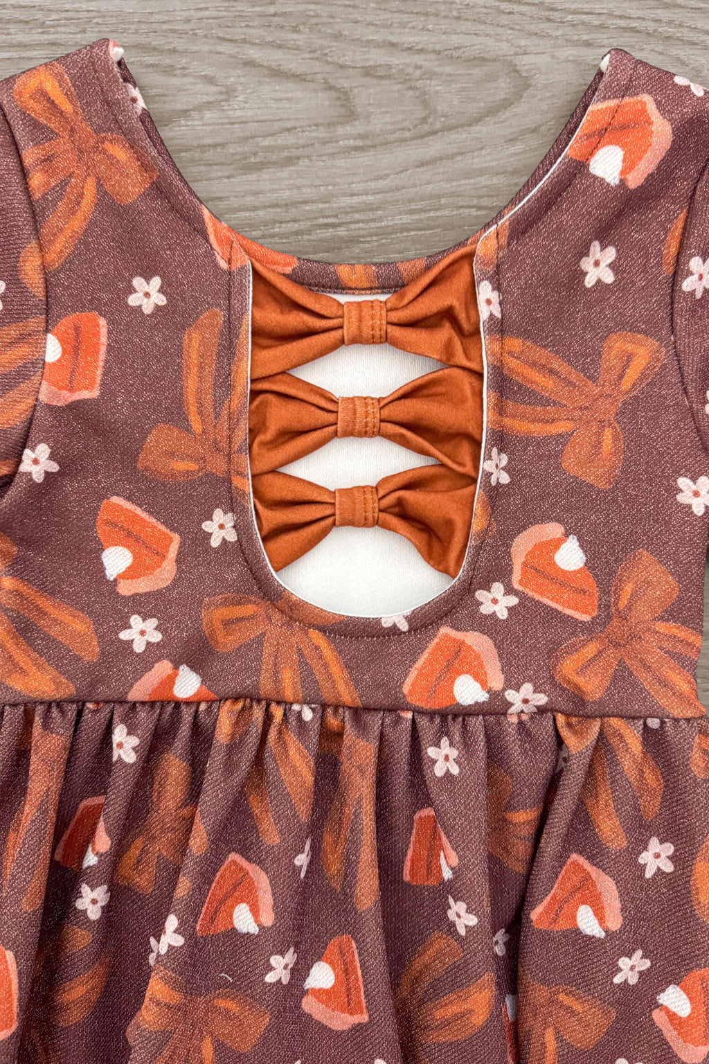 Pumpkin Pie Glitter Dress - 6-12 Months - Brown sleeveless dress with orange bows and a cutout back, featuring glittery pumpkin pie and autumn-themed print.