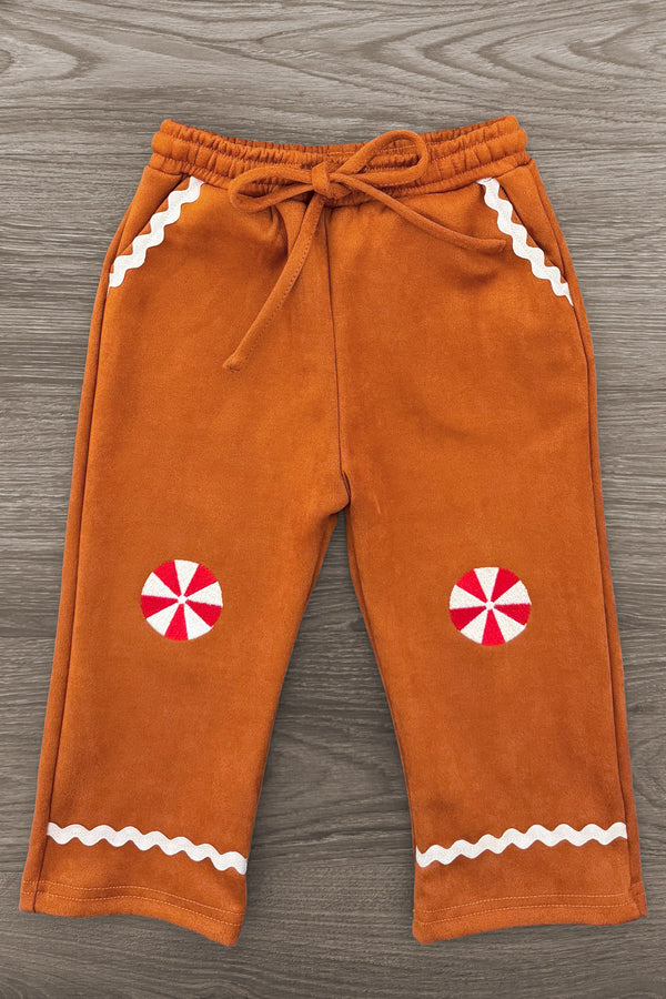 Gingerbread Man Costume - 6-12 Months - Brown soft fabric pants with white zigzag trim and red-and-white peppermint candy patches on knees.