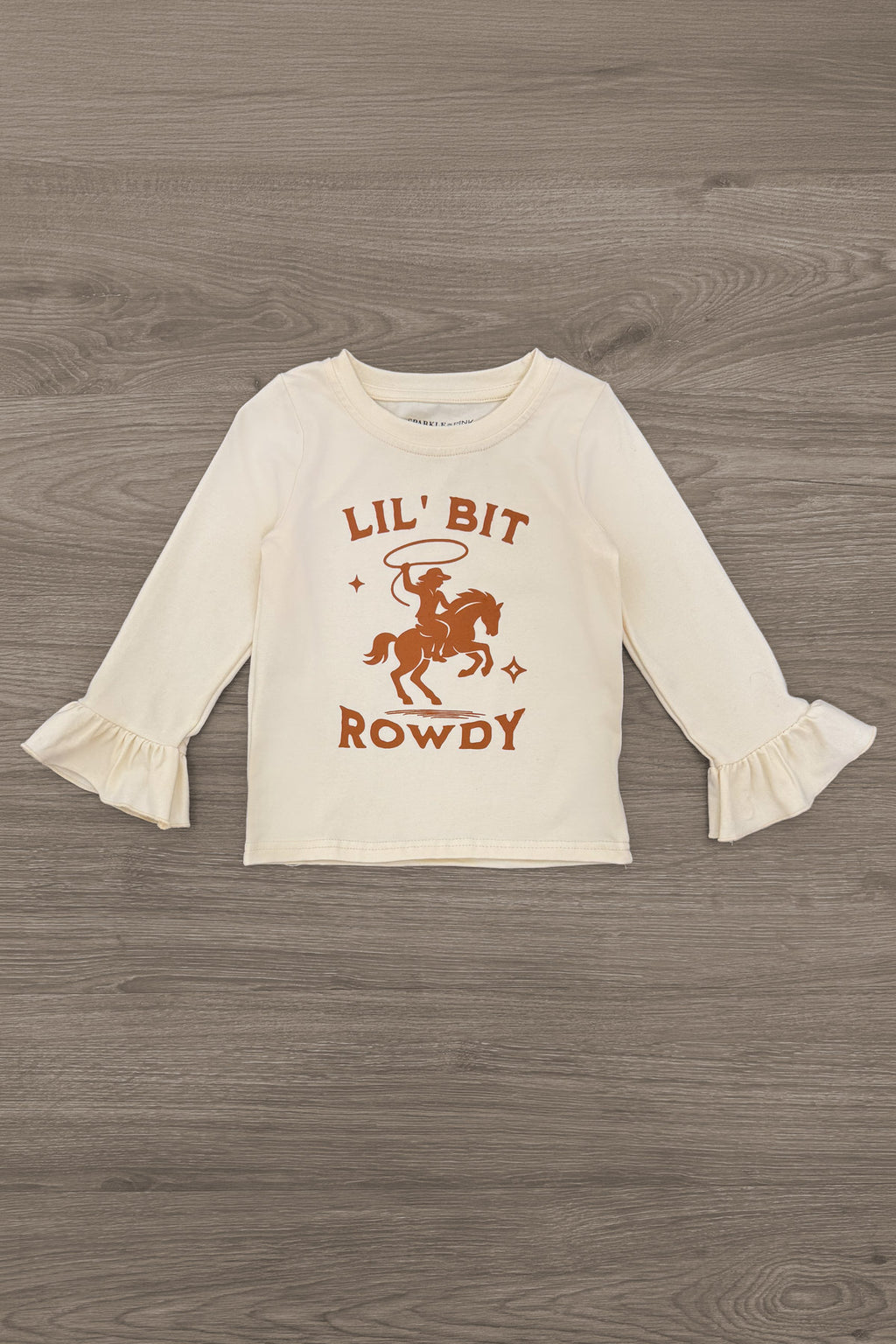 "Lil' Bit Rowdy" Suede Skirt Set - 6-12 Months - Cream long-sleeve toddler top with rust orange cowboy graphic and ruffled cuffs.