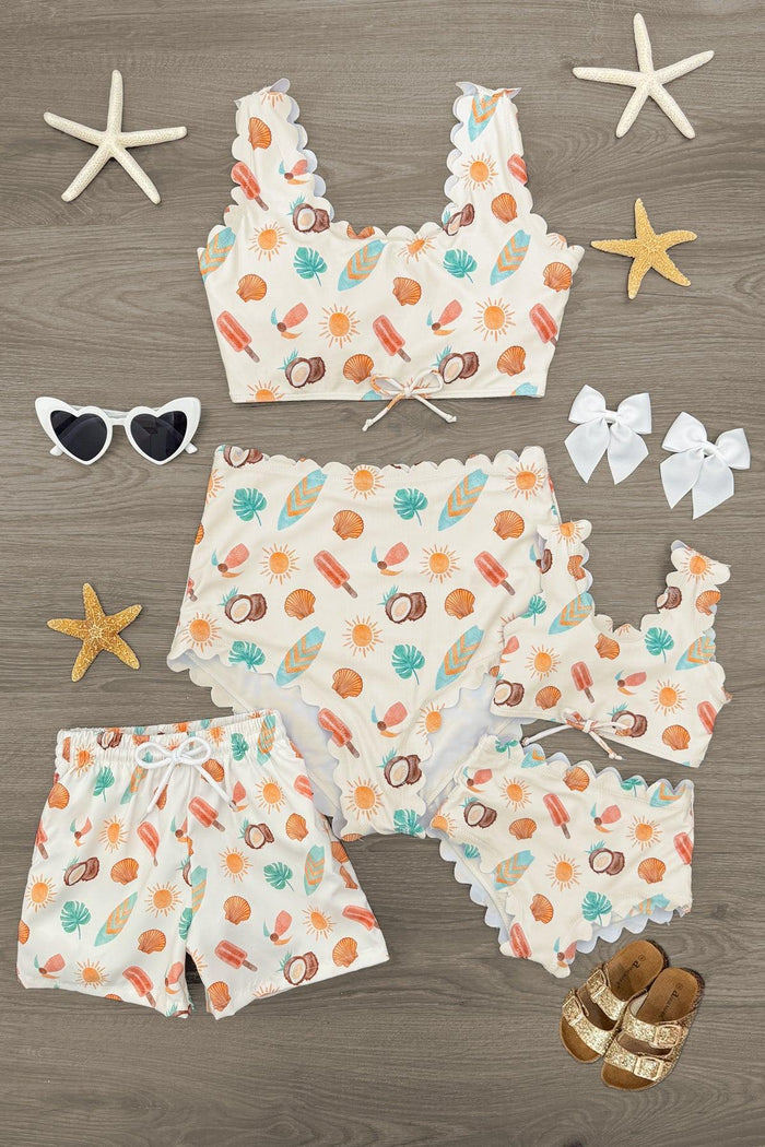 White tropical print mom and kid swimsuits with pineapples and seashells, featuring high waist and ruffled straps.