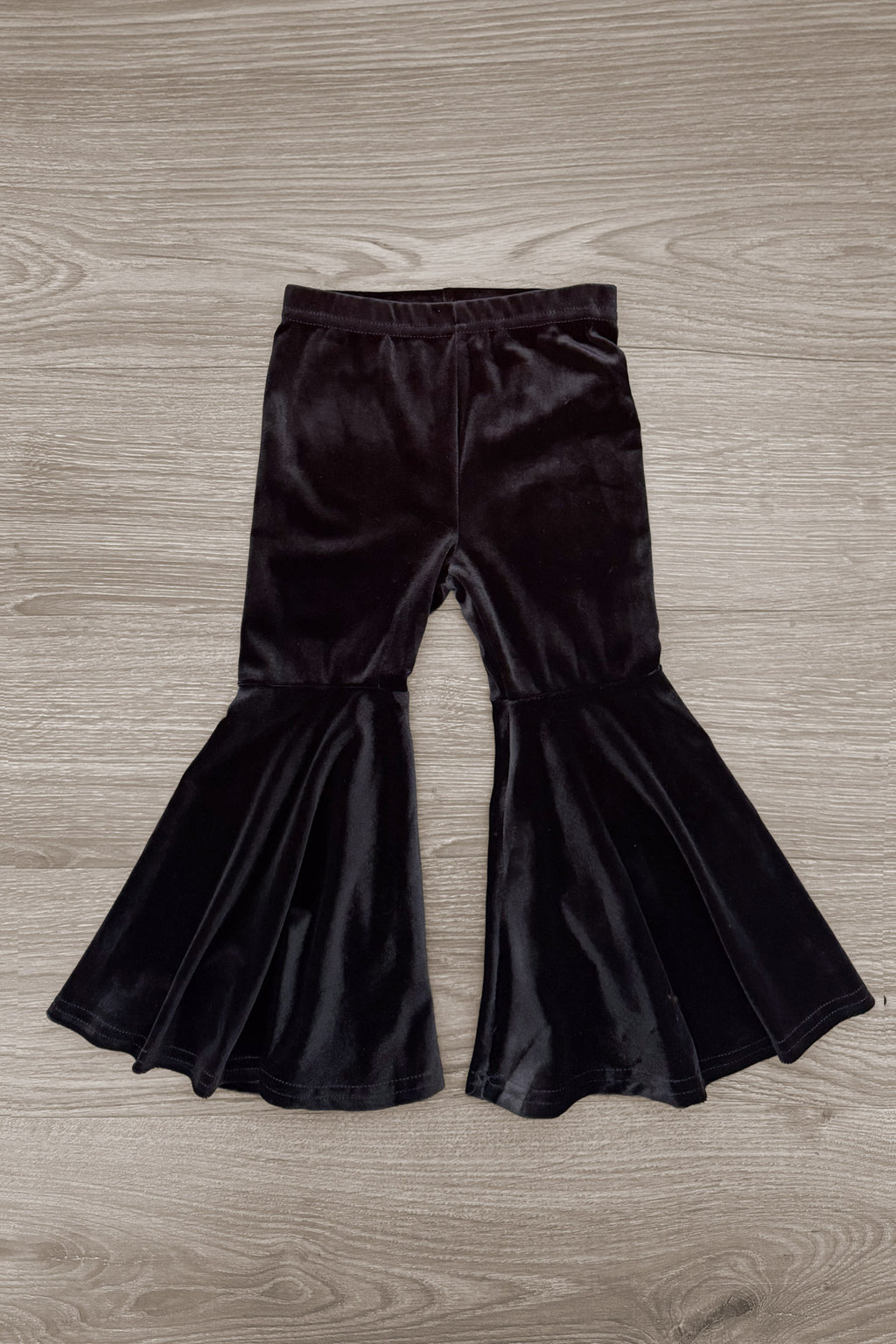 "Boo" Velvet Bell Bottom Set - 6-12 Months - Black velvet bell bottom pants with high waist and wide flared legs on wooden floor background.