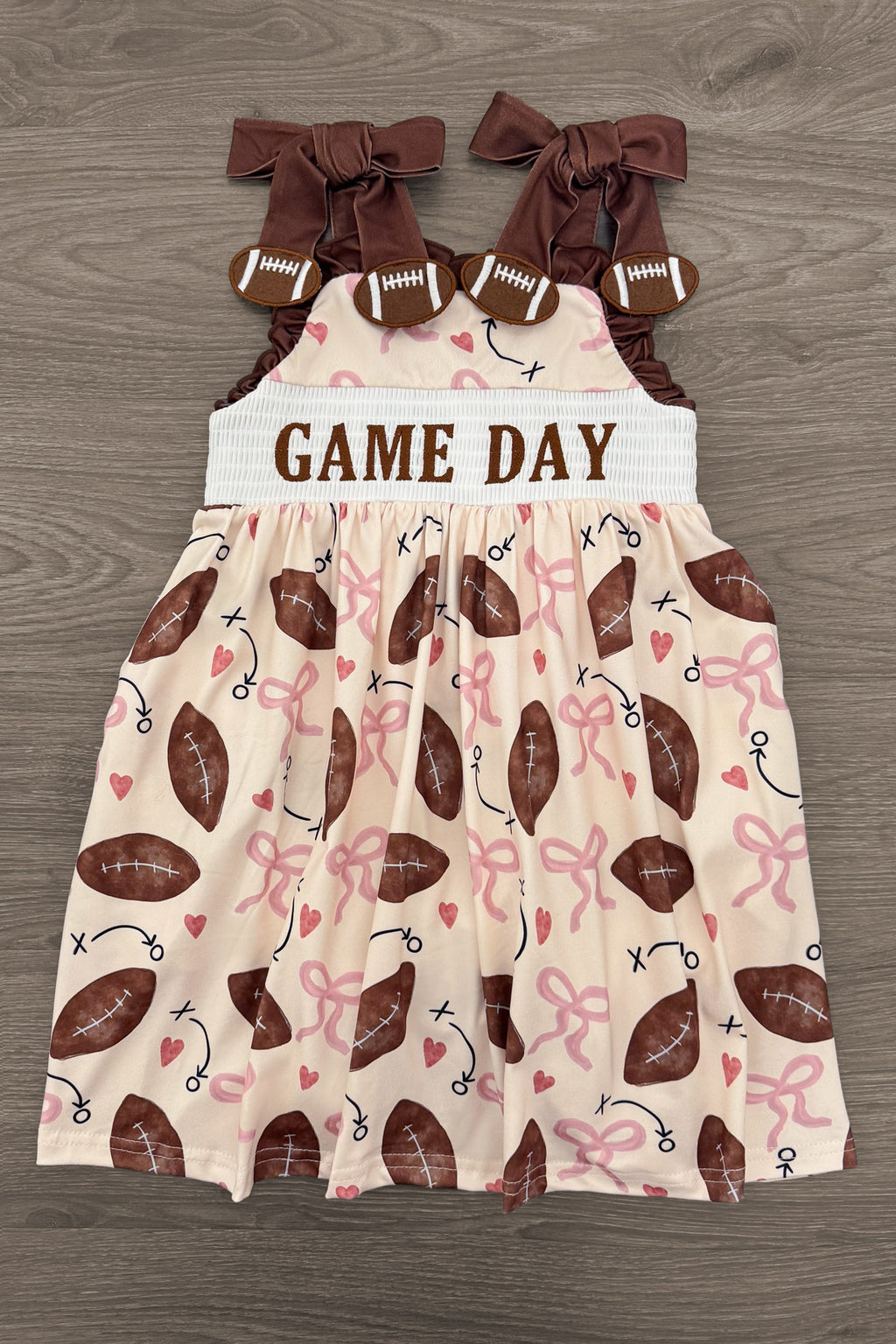 "Game Day" Football Bow Dress - 6-12 Months - Brown and cream toddler dress with football print, "GAME DAY" text, and large brown shoulder bows.