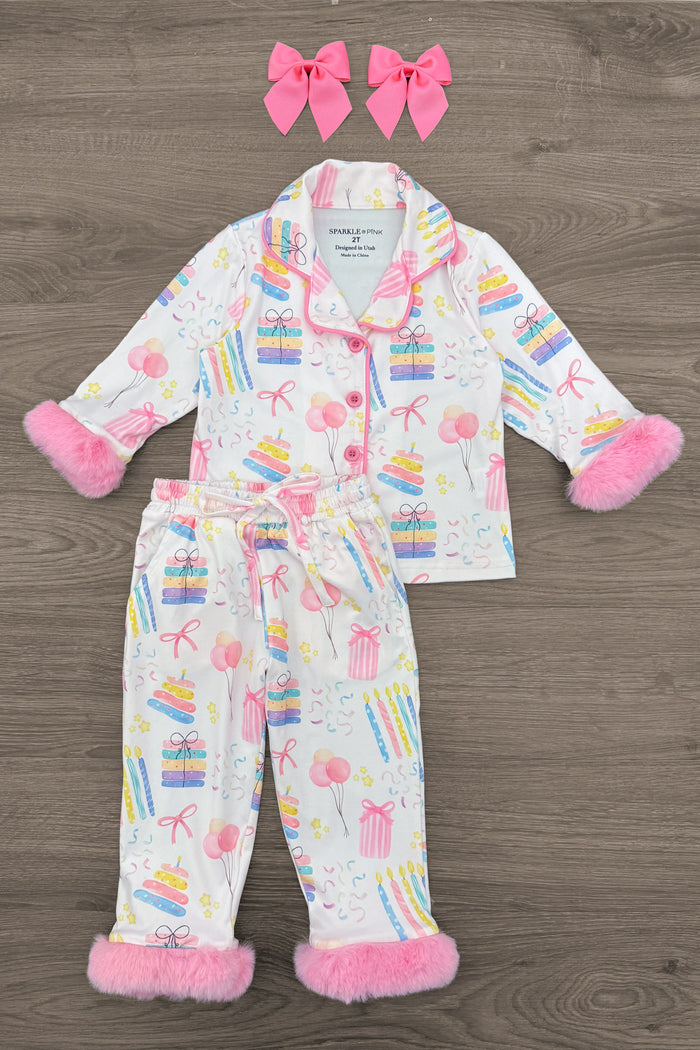 Fuzzy Pastel Pink Birthday Pajamas - 12-18 Months - White long-sleeve pajama set with colorful birthday-themed prints, fuzzy pastel pink cuffs, collar, and pant hems, paired.