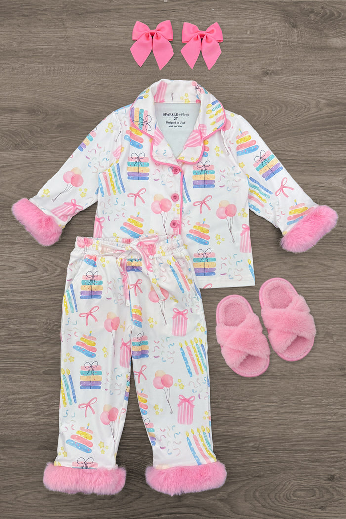 Fuzzy Pastel Pink Birthday Pajamas - 12-18 Months - Fuzzy pastel pink birthday-themed pajamas with matching slippers and two pink hair bows, featuring colorful party icons and.
