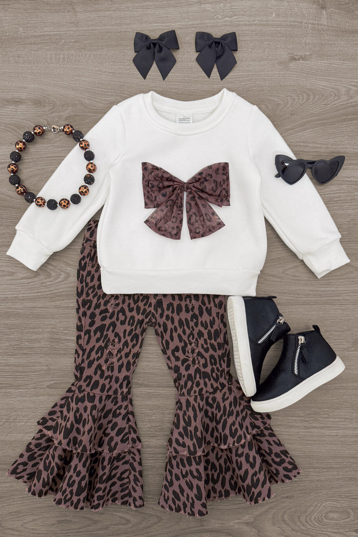 Cheetah Bow Denim Bell Bottom Set - 6-12 Months - White long-sleeve top with a leopard-print bow and bell-bottom pants, styled with black bows and sneakers.