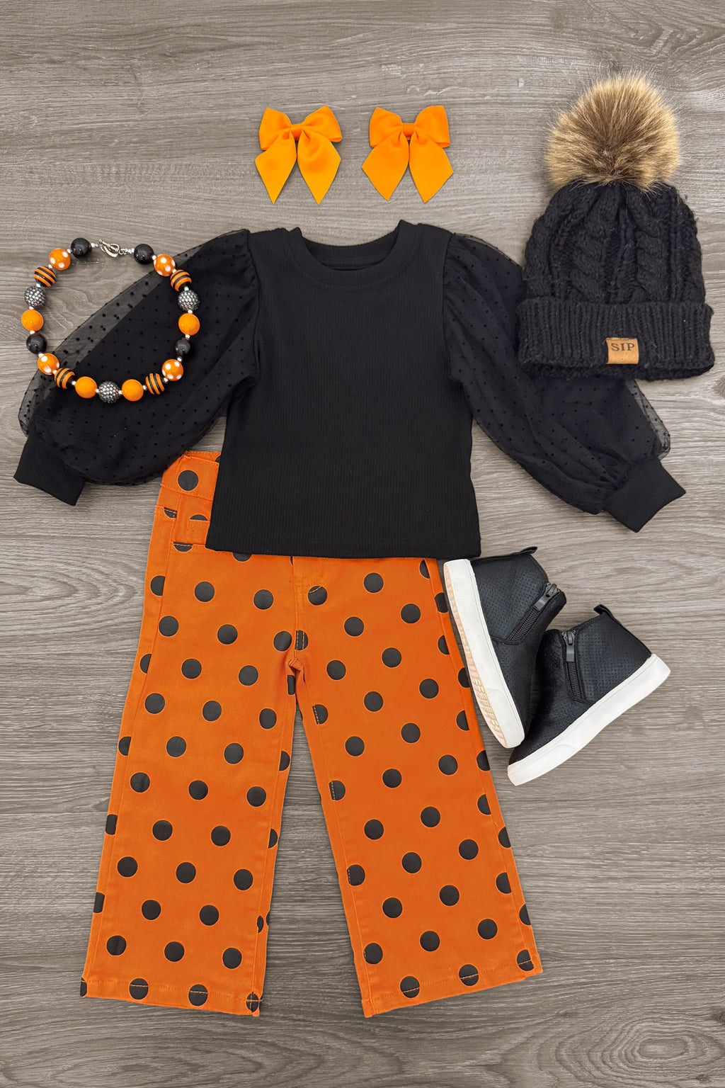 Black & Orange Polka Dot Denim Pant Set - 6-12 Months - Black long-sleeve top with orange polka-dot wide-leg pants, paired with orange bows, beaded necklace, and black knit hat.