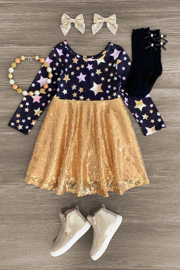 Gold Sequin Star Dress - 3XS-6-12 Months - Black long-sleeve dress with gold star print and gold sequin skirt, paired with black socks, white shoes, beige bows, and.
