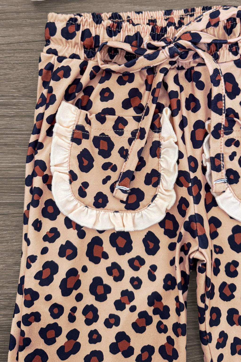 "Thankful" Cheetah Bow Pant Set - 6-12 Months - Beige pants with dark brown and black cheetah print, elastic waistband, and large front pockets trimmed with white ruffles.