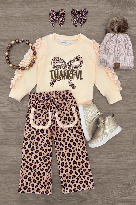 "Thankful" Cheetah Bow Pant Set - 6-12 Months - Cream long-sleeve top with ruffle sleeves and "Thankful" text with leopard bow, paired with wide-legged leopard print pants.