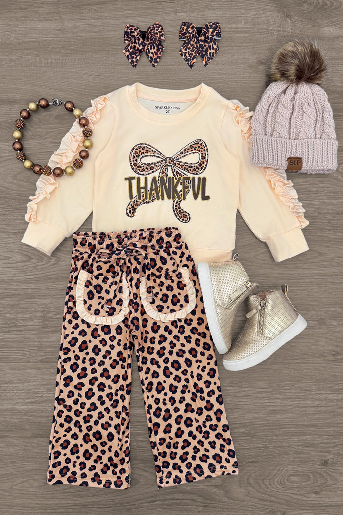 "Thankful" Cheetah Bow Pant Set - 6-12 Months - Cream long-sleeve top with ruffle sleeves and "Thankful" text with leopard bow, paired with wide-legged leopard print pants.