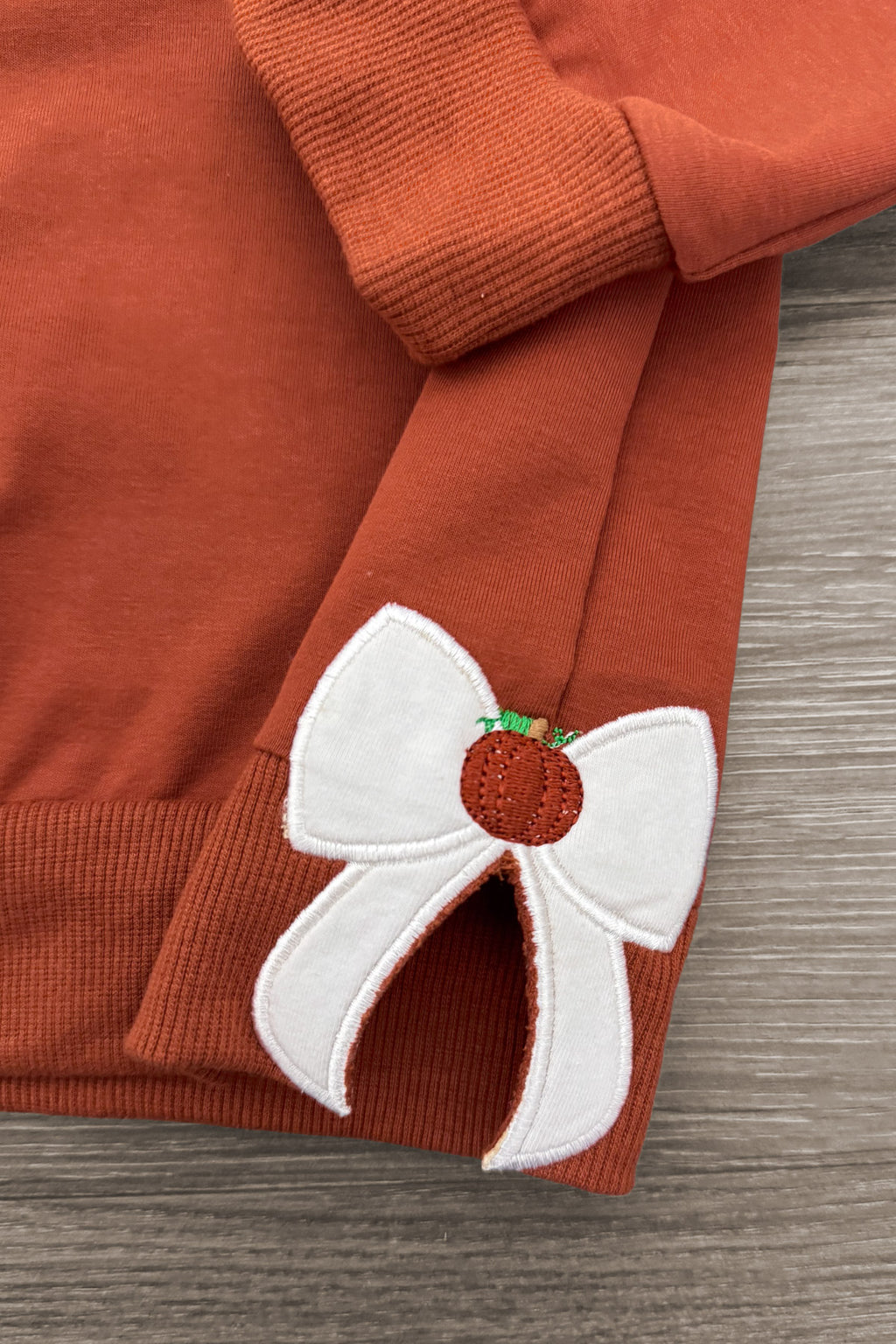 Mom & Me - "Thankful" Bow Pullover - CHILD-6-12 Months - Rust brown pullover with ribbed cuffs and a white bow patch featuring a small pumpkin detail.