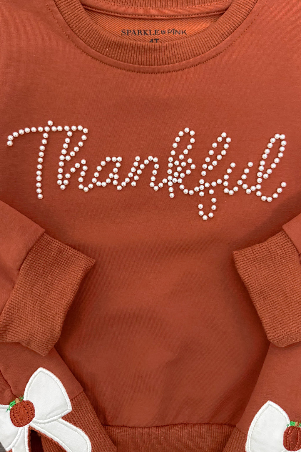 Mom & Me - "Thankful" Bow Pullover - CHILD-6-12 Months - Rust-colored pullover with long sleeves, white pearl-style "Thankful" script across chest, and bow detail with small pumpkin