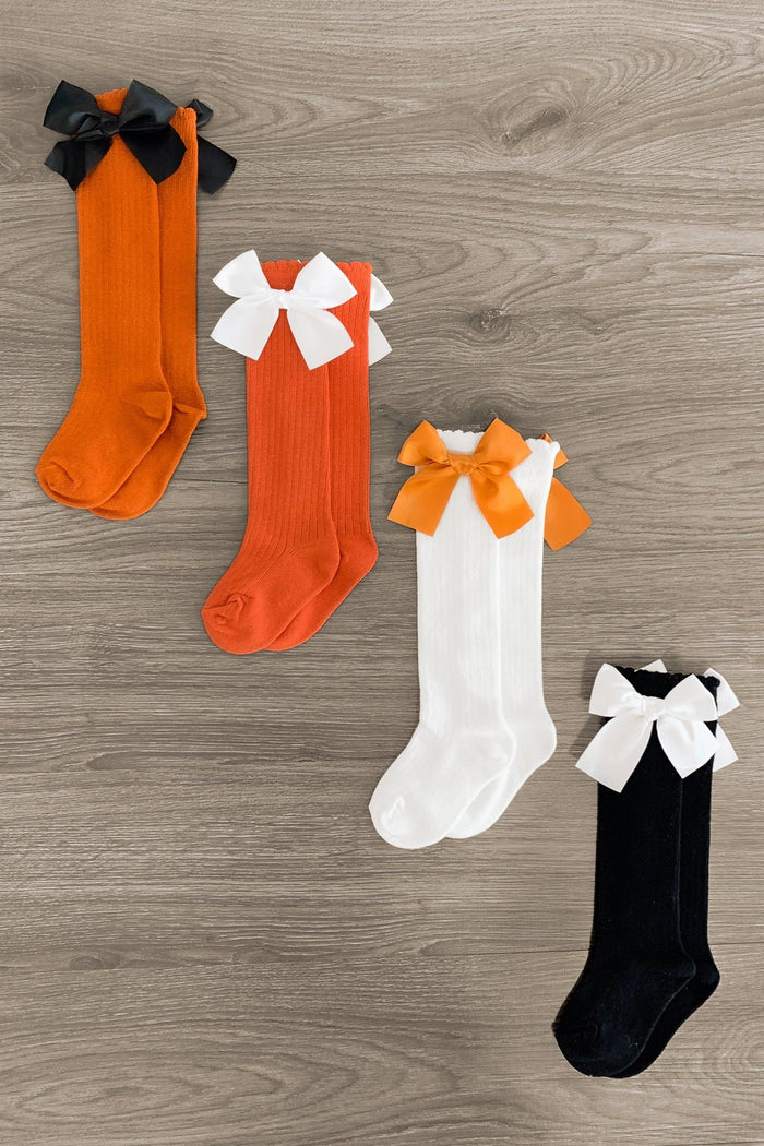 Knee High Silk Bow Socks - White Bow/Rust Sock / Small-3T - Four knee-high socks in black, orange, and white, each with a large contrasting silk bow at the top.