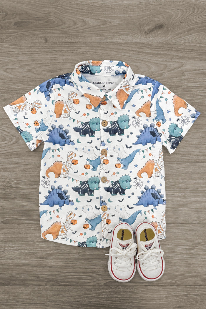 Halloween Dinosaur Button Down Top - 3XS-6-12 Months - White short-sleeve button-down shirt with blue and orange dinosaur print, paired with small white toddler sneakers.