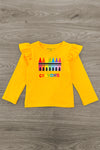 Yellow long-sleeve shirt with colorful crayon design on a wooden surface