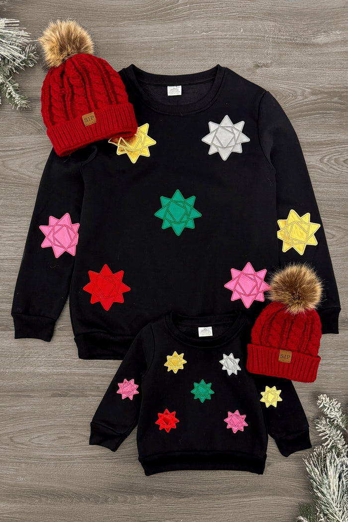 Mom & Me - Christmas Star Sweatshirt - CHILD-3XS-6-12 Months - Black sweatshirt with colorful Christmas star appliques in various sizes, paired with red knit beanies topped with brown.