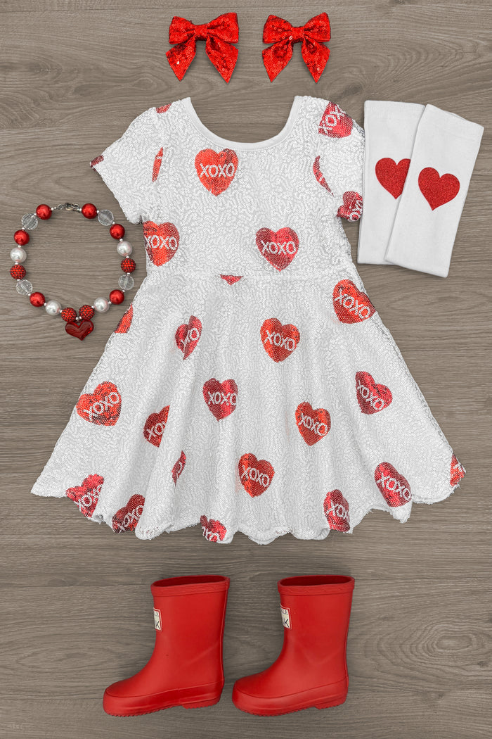"XOXO" Sequin Hearts Dress - 3XS-6-12 Months - White short-sleeve dress with red sequin "XOXO" hearts, paired with red boots, heart-printed knee socks, red bead necklace,.