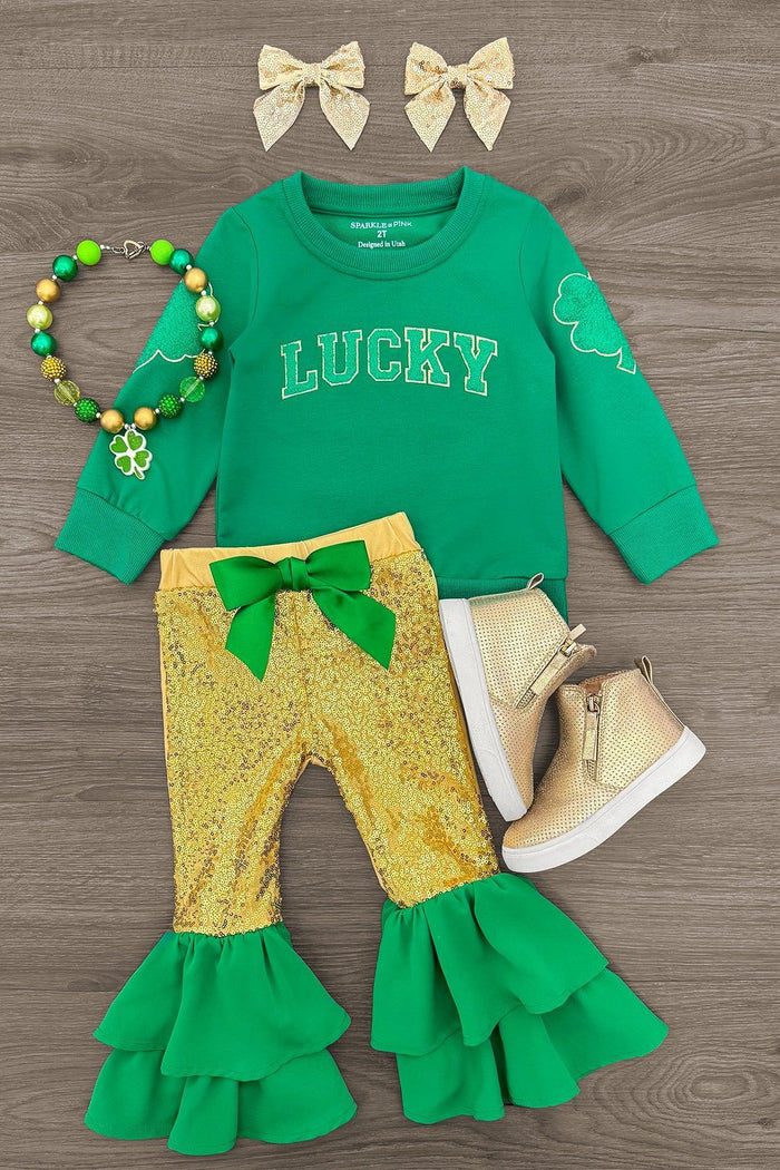 "Lucky" Gold Sequin Bell Bottom Set - 6-12 Months - Green long-sleeve shirt with "Lucky" text, gold sequin bell-bottom pants with green ruffle cuffs, gold shoes, green and gold .