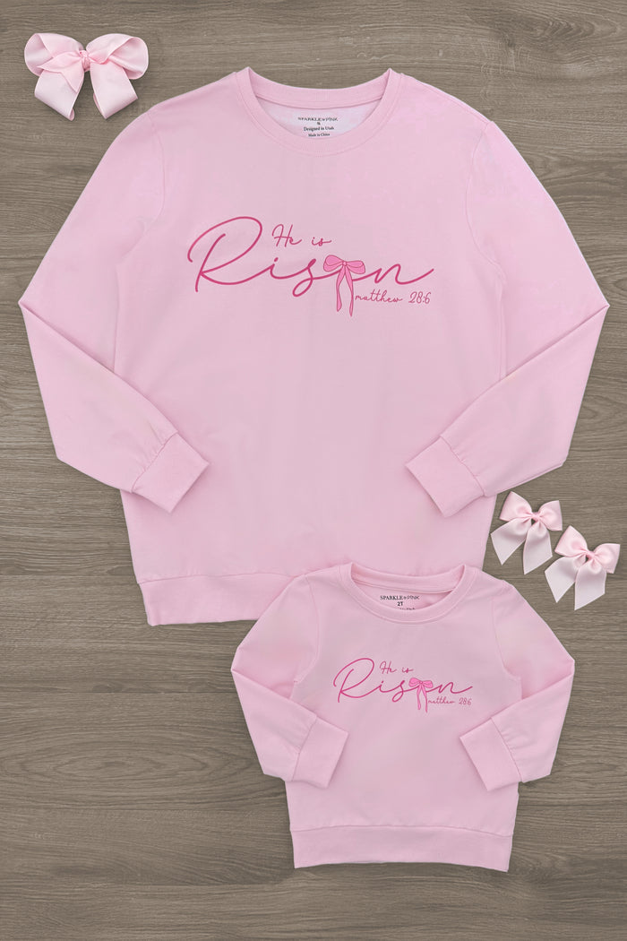 Mom & Me - "He Is Risen" Long Sleeve Top - CHILD-6-12 Months - Matching pink long sleeve tops for mom and child with "He Is Risen" script and bows on wooden floor.