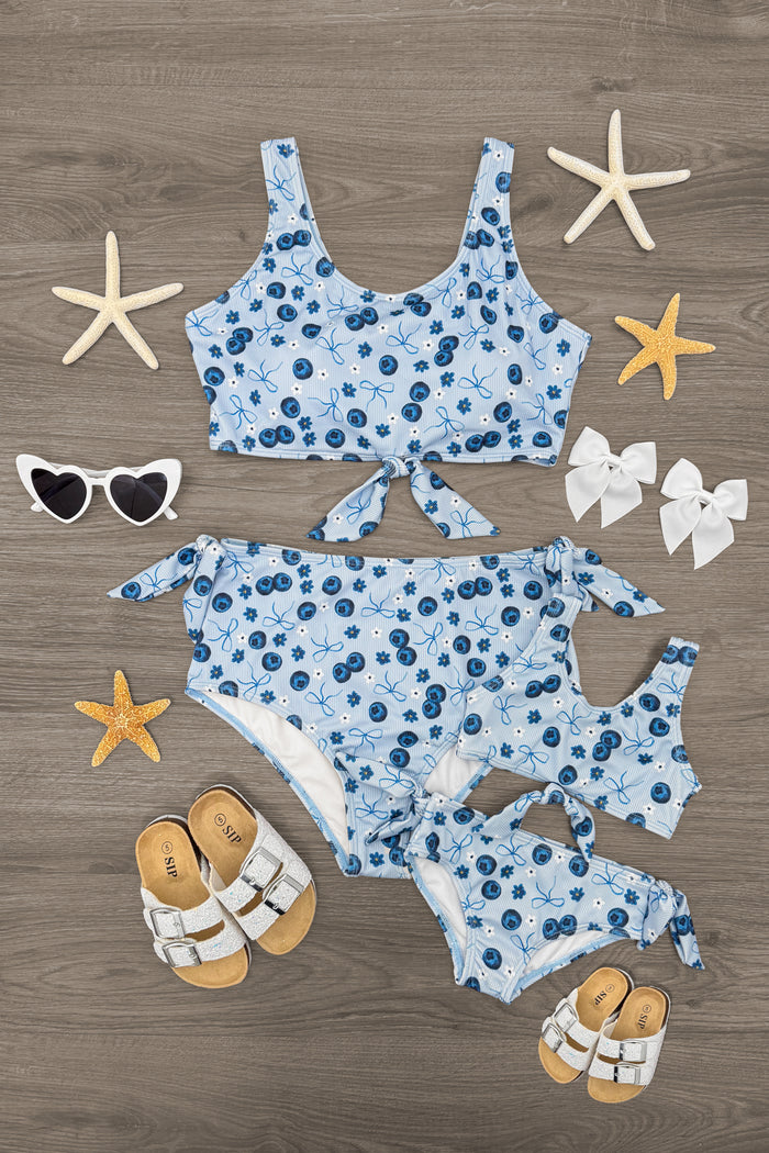 Mom & Me - Blueberries & Bows Bikini - CHILD-6-12 Months - Blueberries print matching mom and child bikinis with tie-front tops and side-tie bottoms on a wood background.