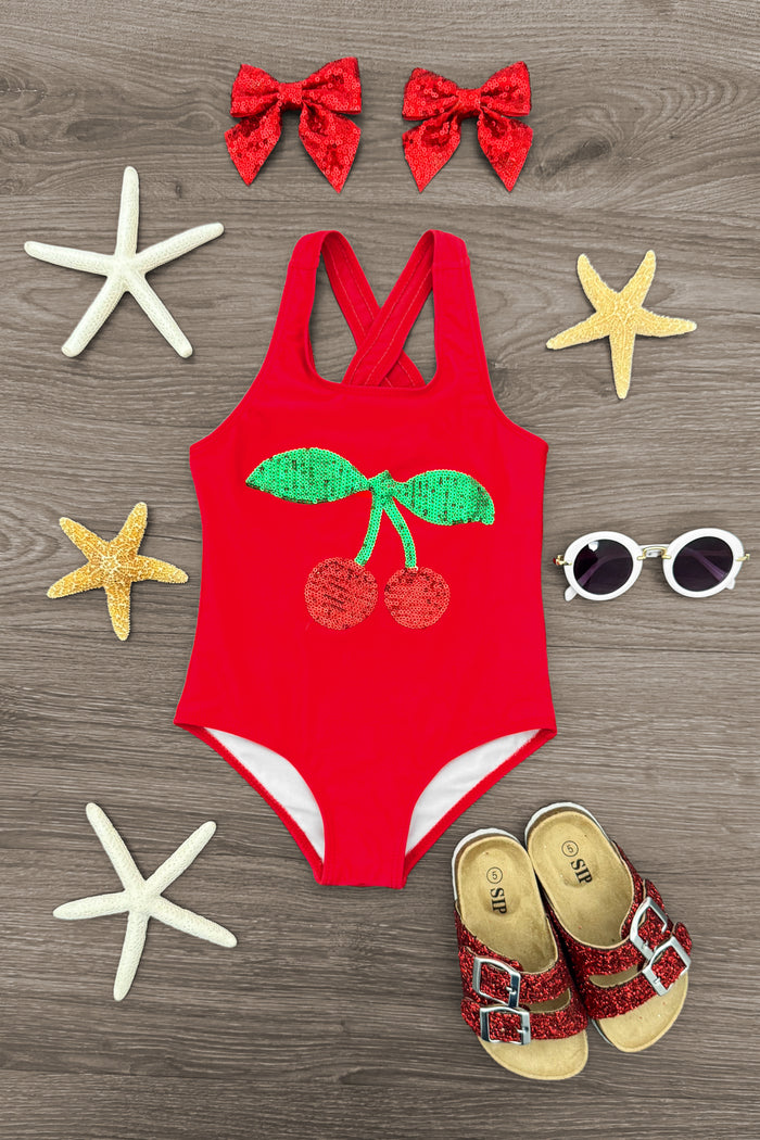 Cherry Sequin Swimsuit - 6-12 Months - Red toddler swimsuit with green sequin cherry design, paired with red bow hair clips and sunglasses.