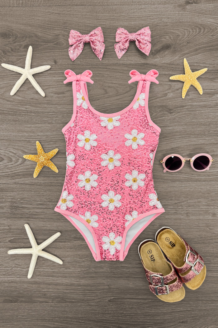 Pink Flower Sequin Swimsuit - 6-12 Months - Pink toddler swimsuit with white daisy sequins, matching pink bows, floral sandals, and round pink sunglasses on wooden floor.