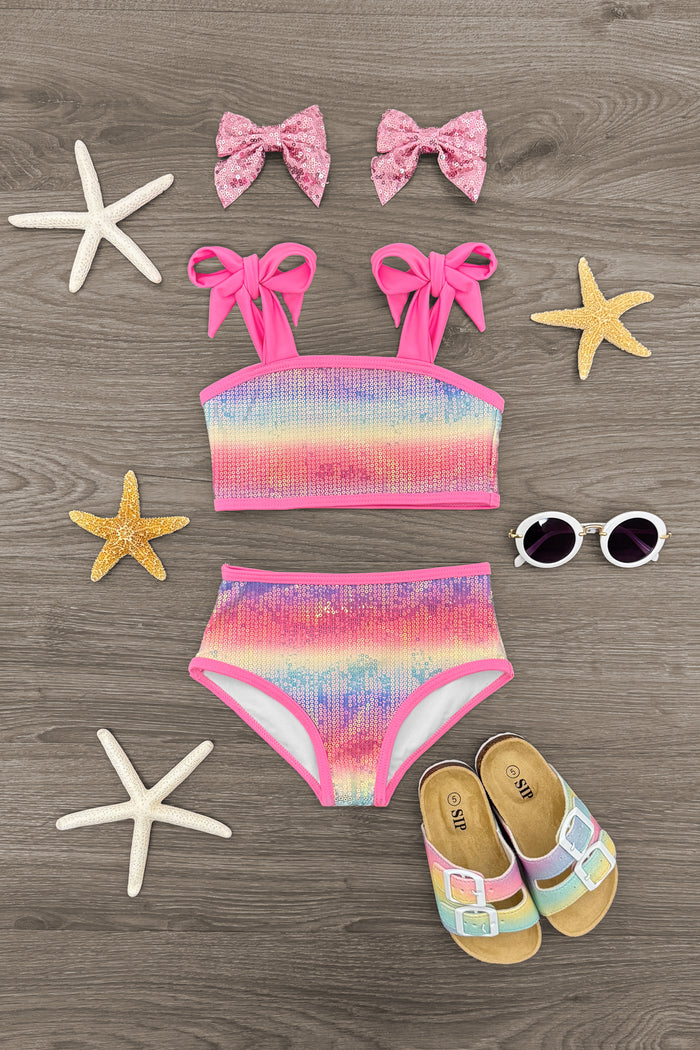 Rainbow Sequin Bikini - 6-12 Months - Rainbow sequin bikini set for toddler with pink bow hair clips, white sunglasses, and rainbow sandals on wooden background.