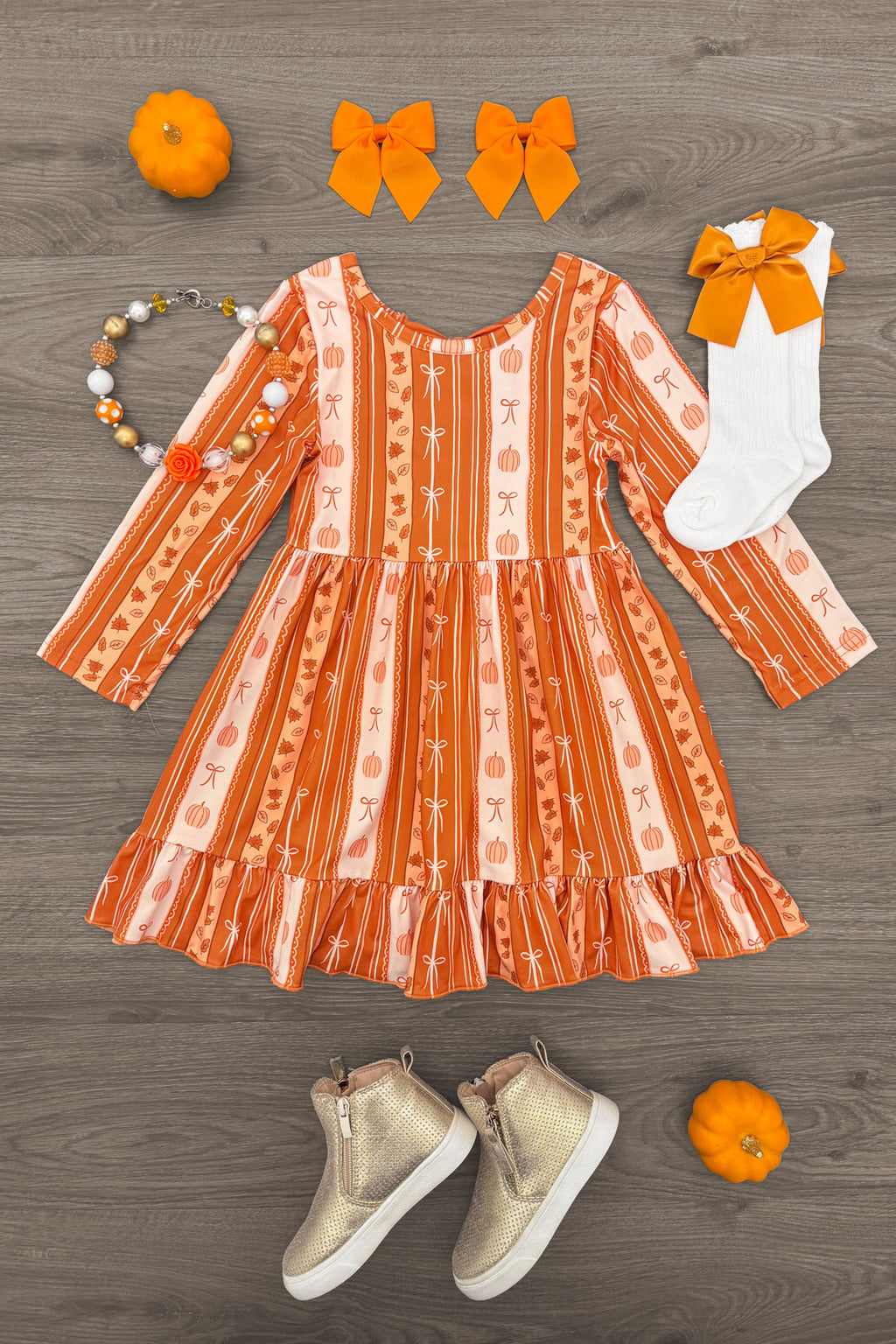 Pumpkins & Bows Stripe Dress - 6-12 Months - Orange long-sleeve striped dress with pumpkin and bow patterns, paired with white socks and orange bow, beige high-top.