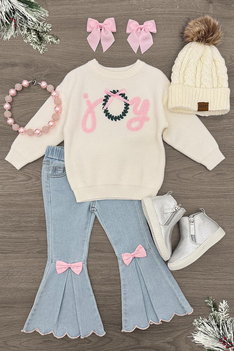 "Joy" Denim Flare Pant Set - 6-12 Months - Cream “Joy” knit sweater paired with light-wash denim flare jeans, pink bows, a beaded bracelet, and white sneakers.