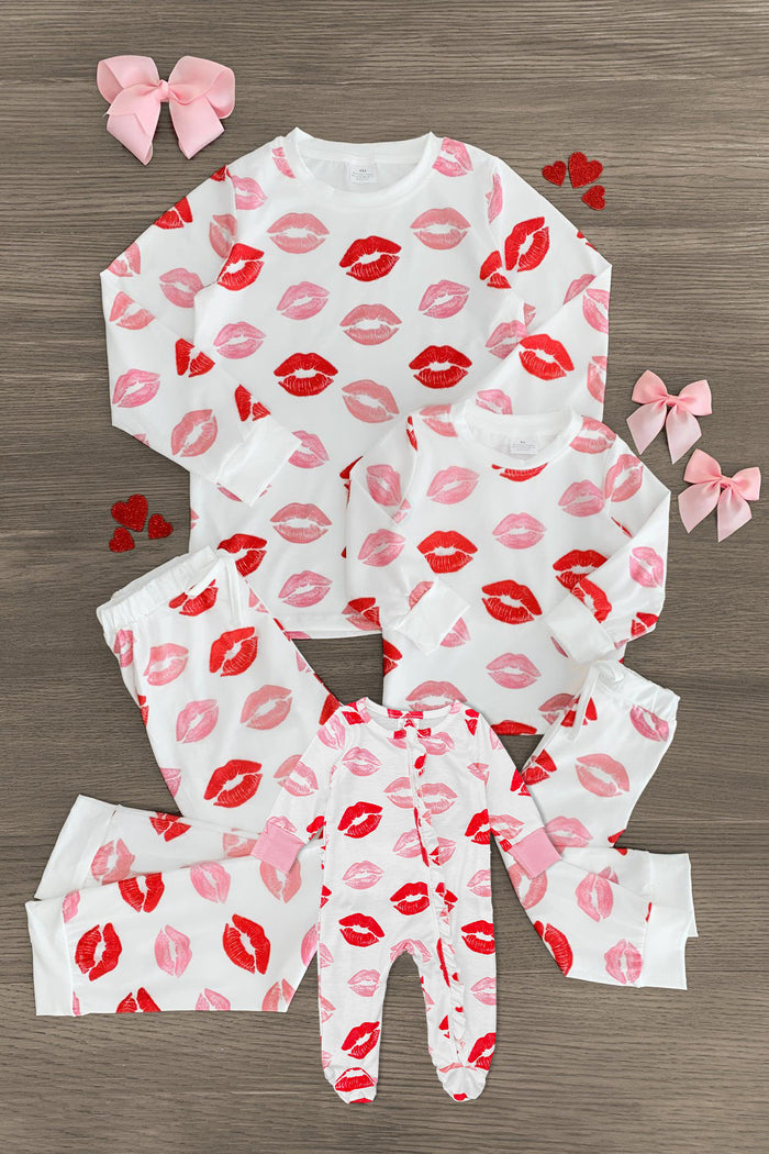Mom & Me - White Lipstick Kiss Pajamas - BABY-Newborn - White pajamas set with red and pink lipstick kiss prints, includes matching infant and child sizes, two pink bows nearby.