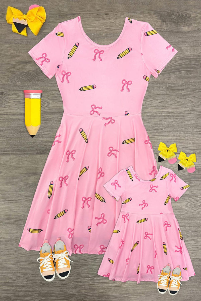 Mom & Me - Pink Pencil & Bow Dress - CHILD-3T - Pink short-sleeve dress with pencil and bow print, matching child and adult sizes, paired with yellow bows and orange shoes.