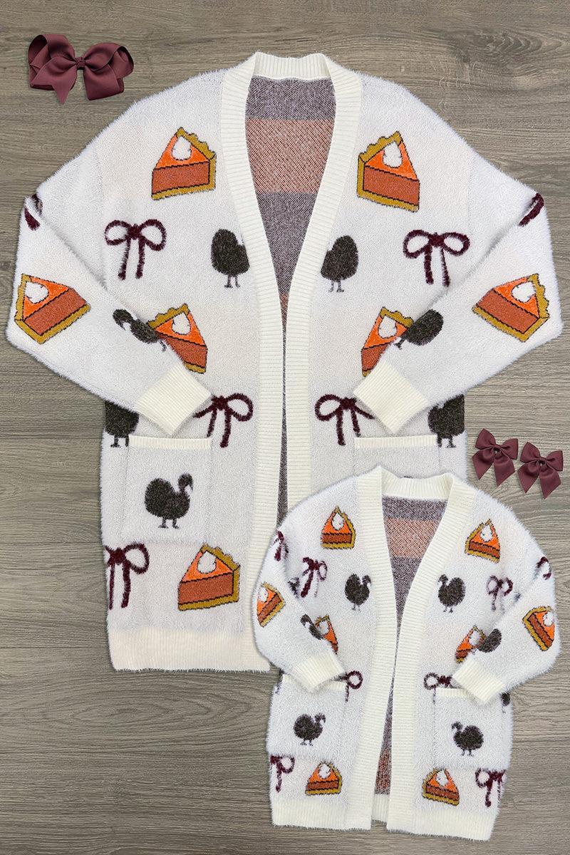 Mom & Me - Cozy Thanksgiving Cardigan - CHILD-6-12 Months - Cream knit cardigan with pumpkin pie and bow motifs, featuring large front pockets and button closure.