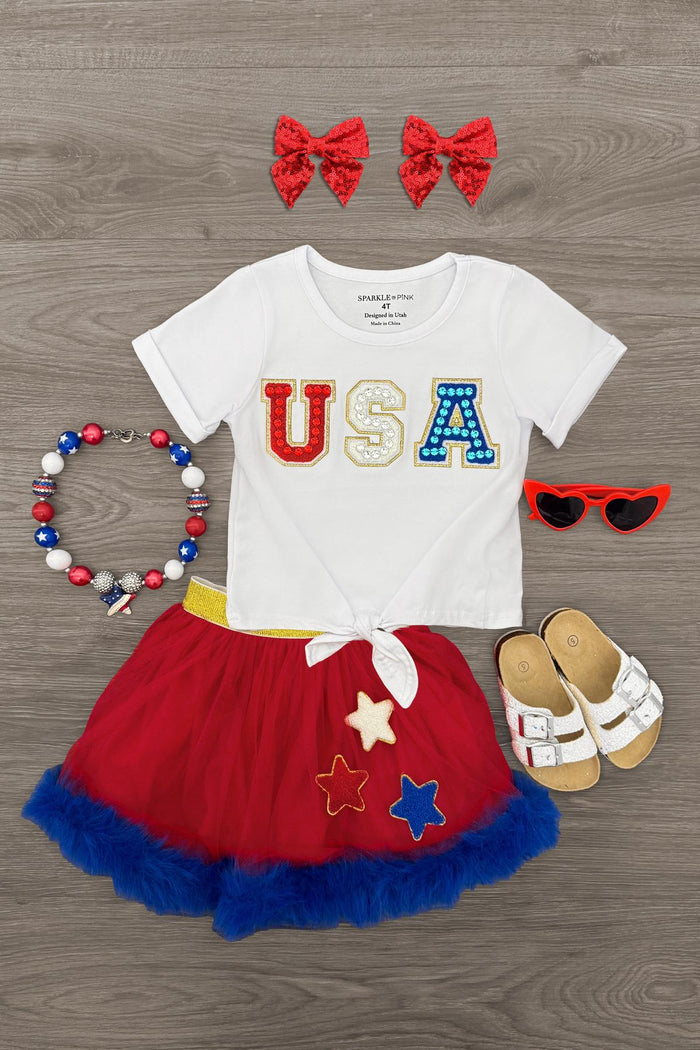 "USA" Tutu Skirt Set - 3-6 Months - White toddler T-shirt with red, yellow, and blue USA letters, red and blue tutu skirt with stars, red bow headbands, red.