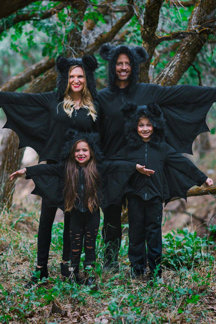 Family Bat Costume - CHILD-3XS-6-12 Months-FAMILY - Family wearing black bat costumes with wings and ears outdoors among trees.
