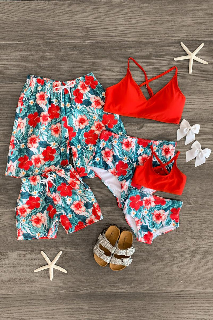 Red tropical floral two-piece swimsuit for girls, matching cover-up and sandals on wood floor.