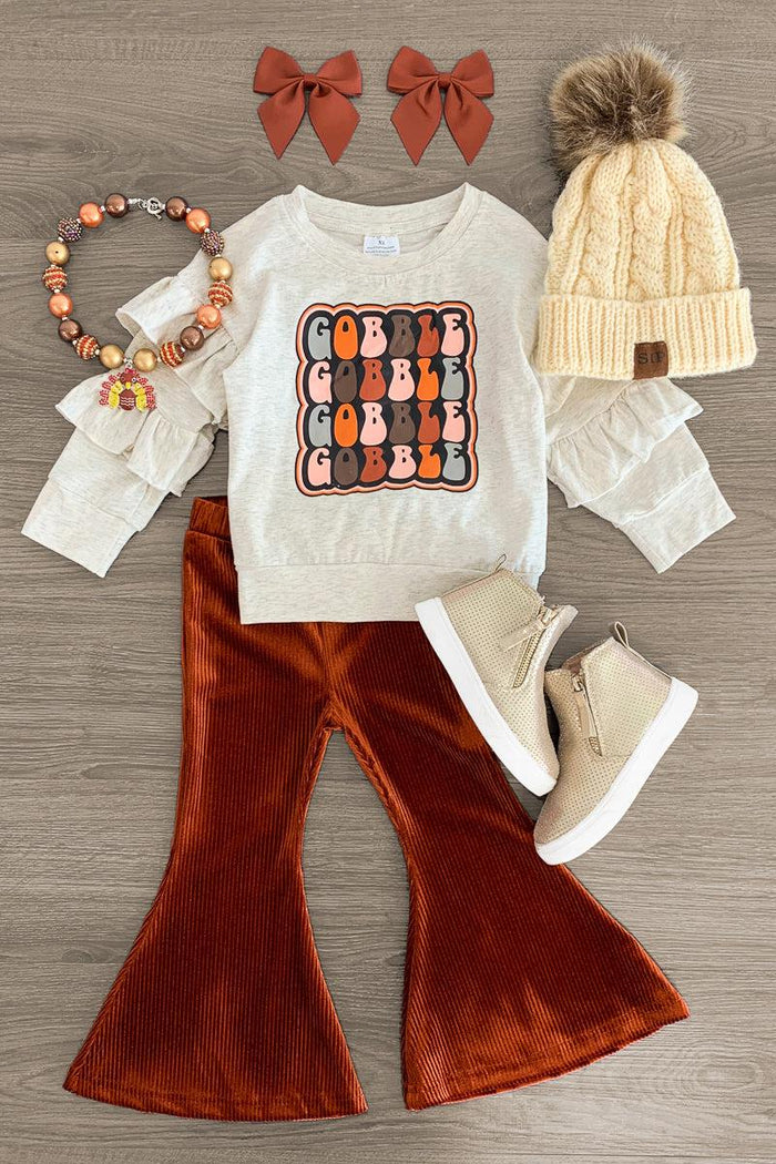 "Gobble" Bell Bottom Set - 3XS-6-12 Months - Cream long-sleeve shirt with "GOBBLE GOBBLE" print, rust bell-bottom pants, cream knit hat with pom-pom, beige boots, brown.