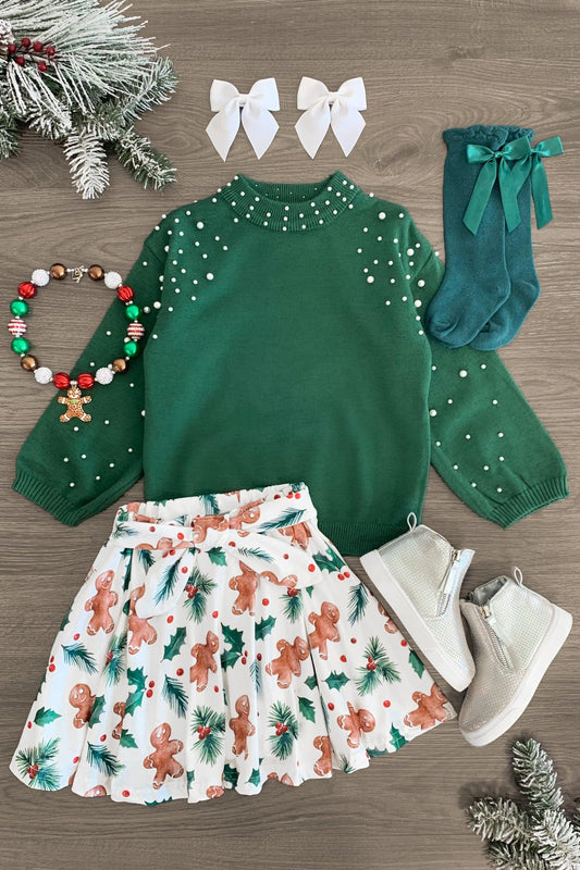 Holly Gingerbread Pearl Skirt Set - 3XS-6-12 Months - Green long-sleeve sweater with pearl accents, white skirt with gingerbread print, white boots, green socks with bows, two.